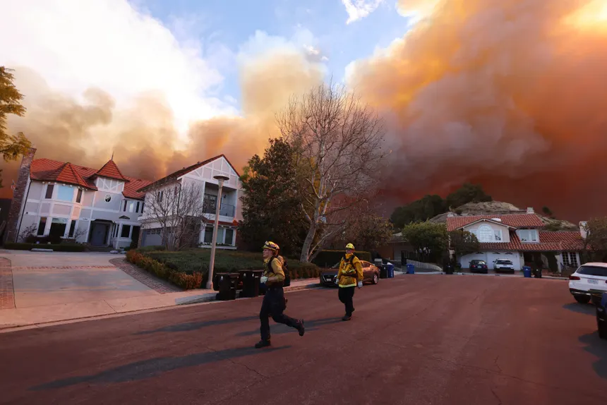 Firefighters walking through a residential neighborhood under wildfire smoke during the Los Angeles Palisades Fire